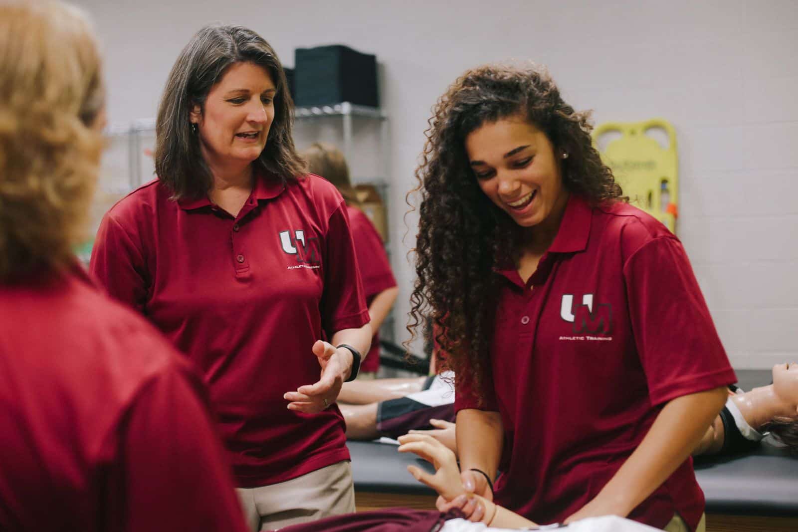 Individuals in maroon polo shirts engaged in a training session with a leader and participants.