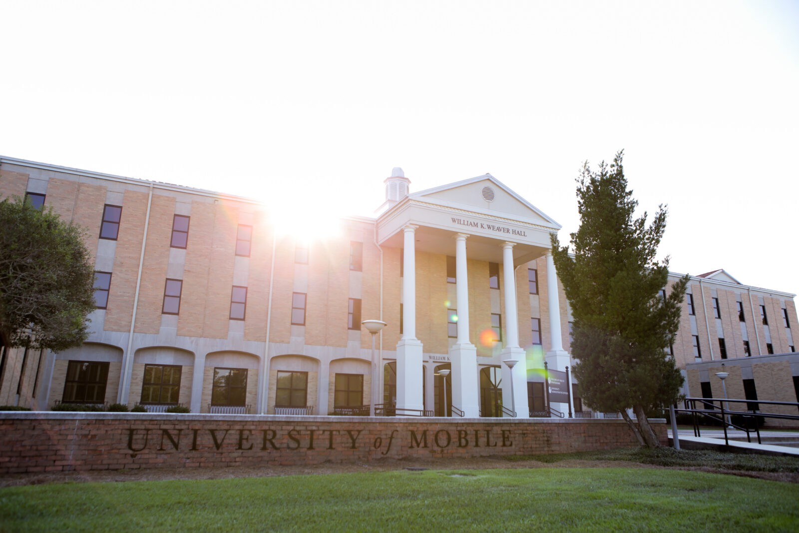 University of Mobile building with columns and sunset glow in the background