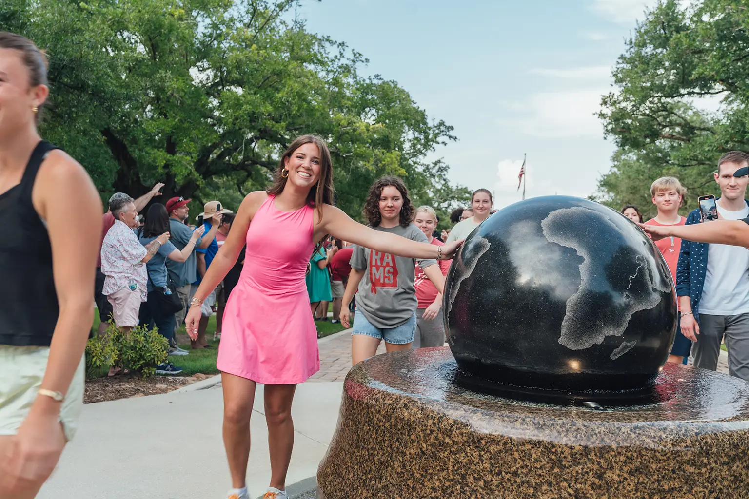 people touching globe statue